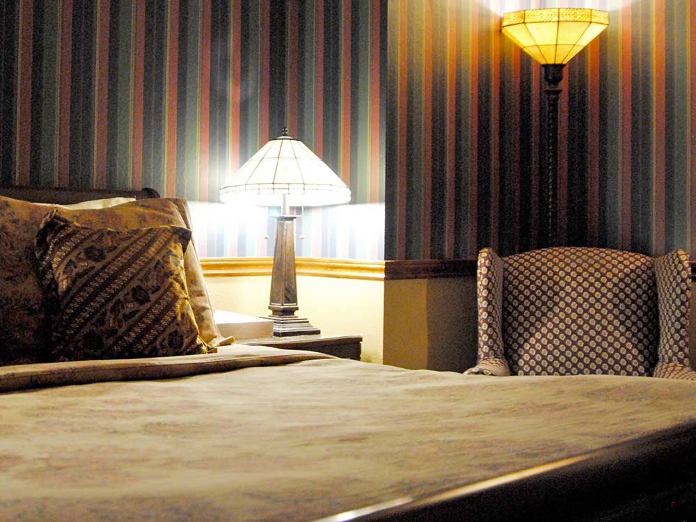 chair and lamp near bed with decorative pillow